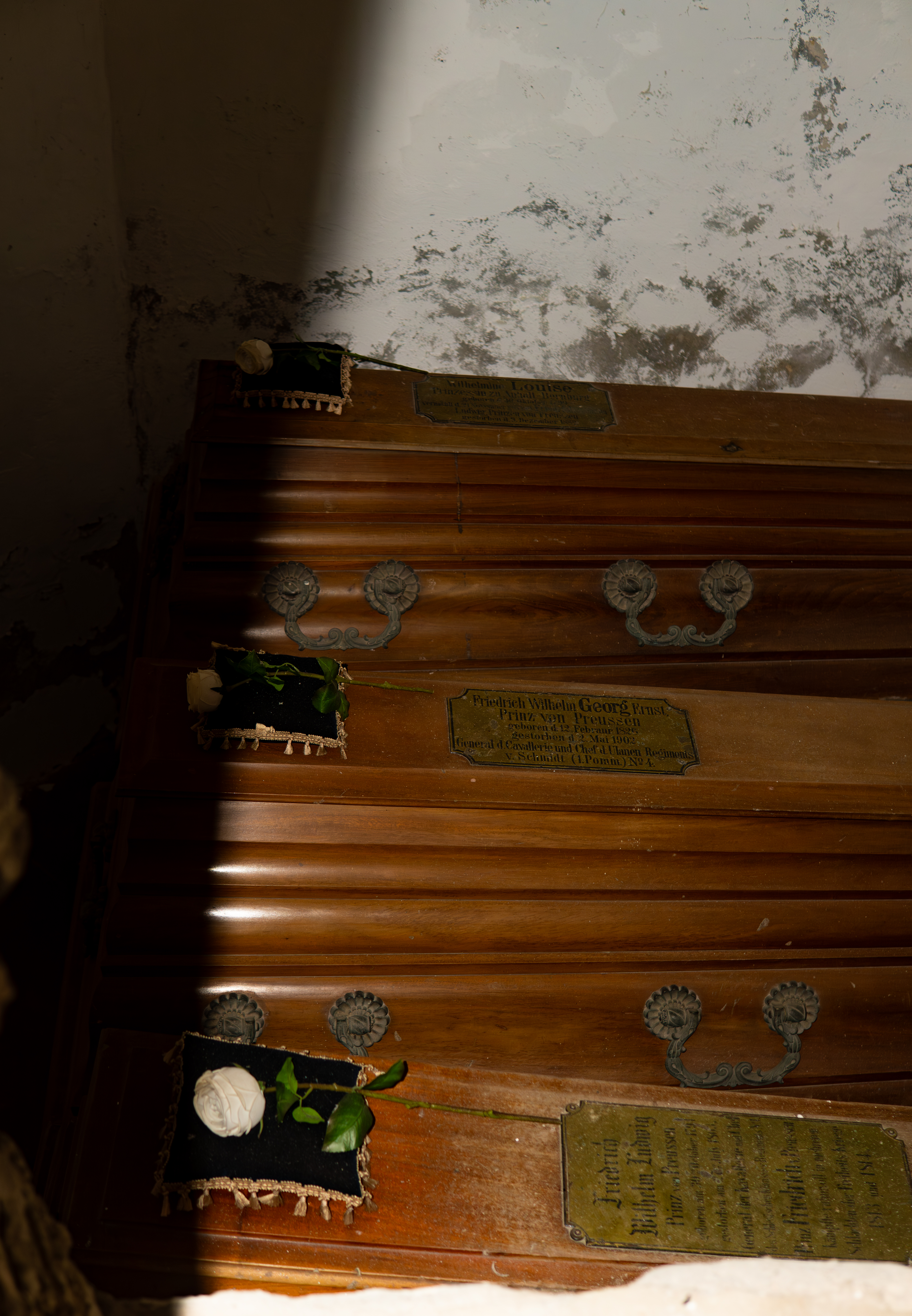 Drei Särge unter der Kapelle, sanft von Licht geteilt, mit weißen Rosen